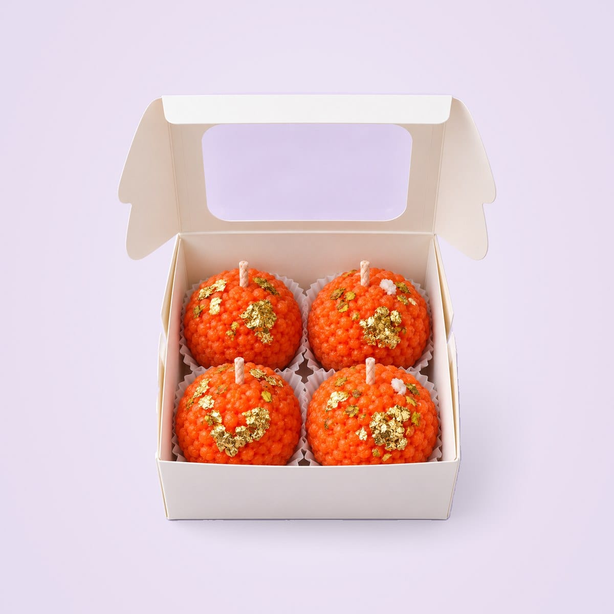 Four motichoor laddu candles in a white window box
