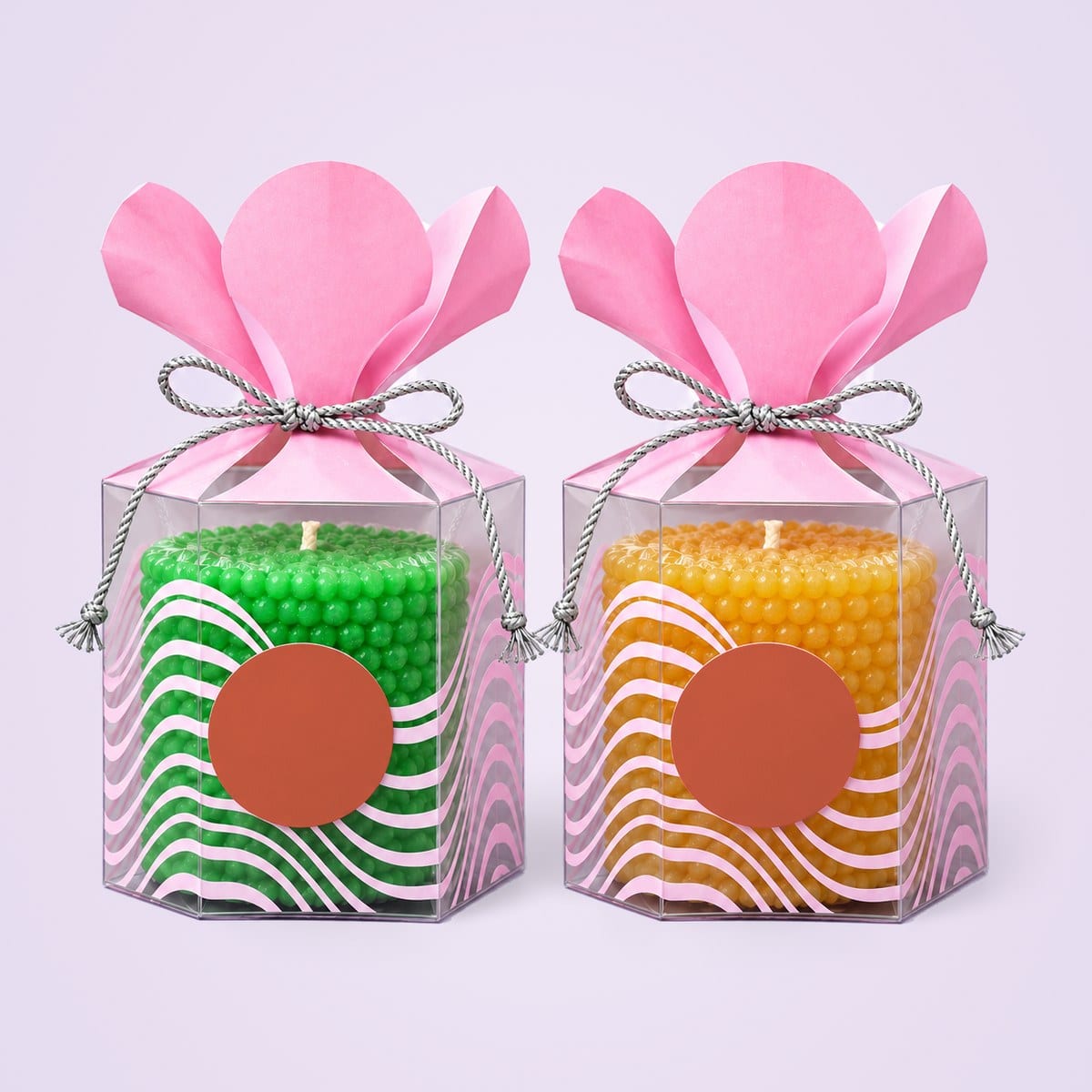 Green and yellow pearl pillar candles in clear hexagonal gift boxes with pink petal tops