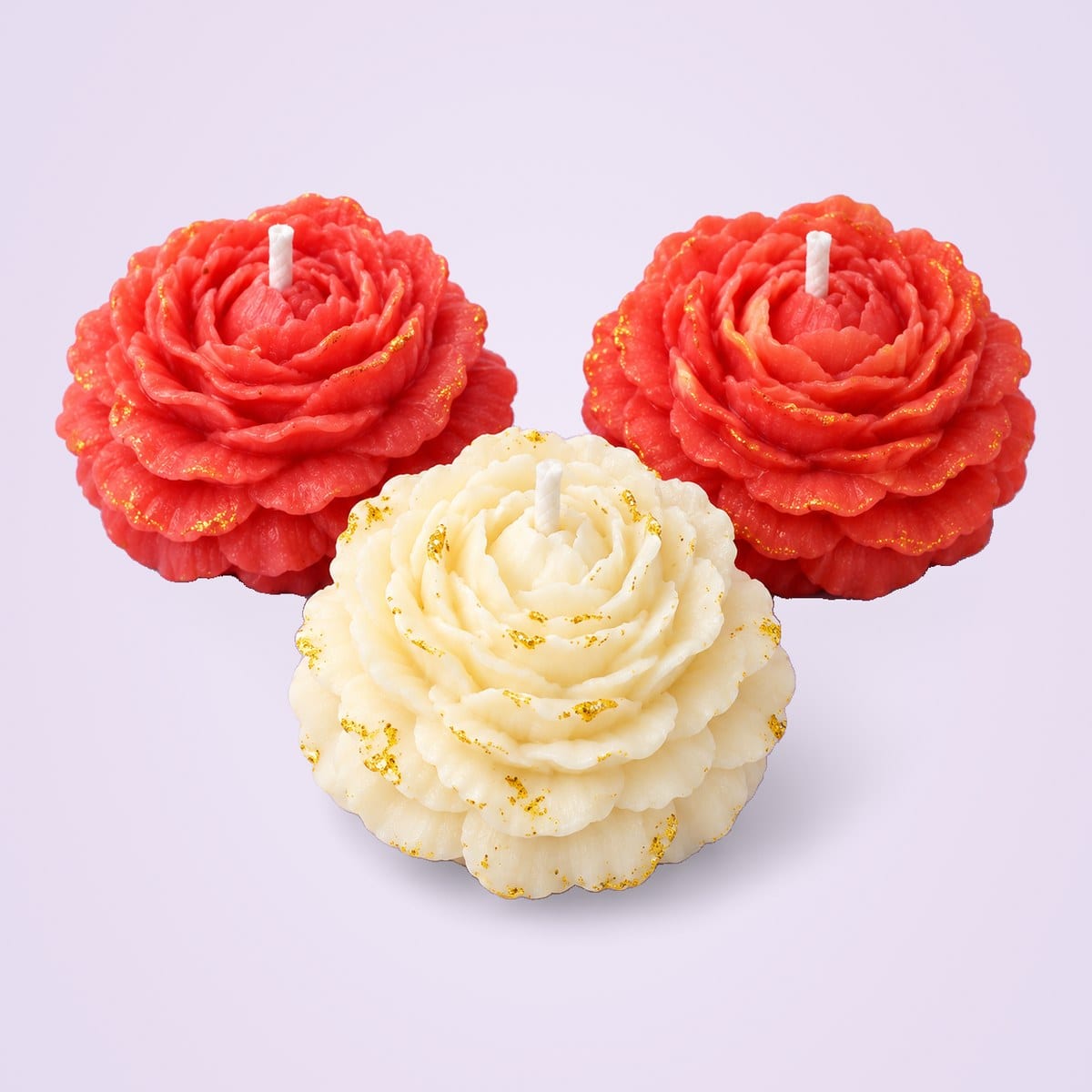 Two red peony candles and one ivory peony candle, with gold glitter on the petals