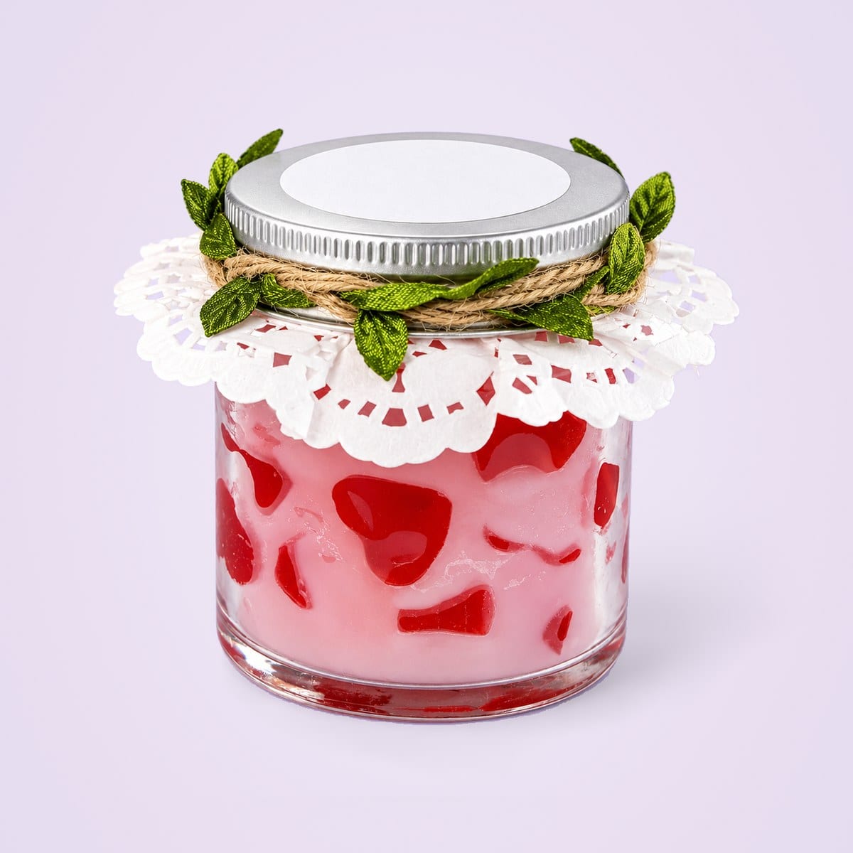 Glass jar candle with red wax hearts in pale pink wax, a silver lid and a lace doily
