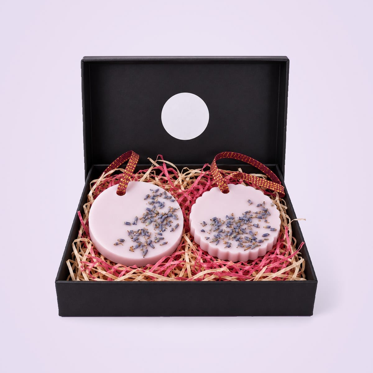 Round and scalloped lilac wax sachets with lavender buds in a black gift box
