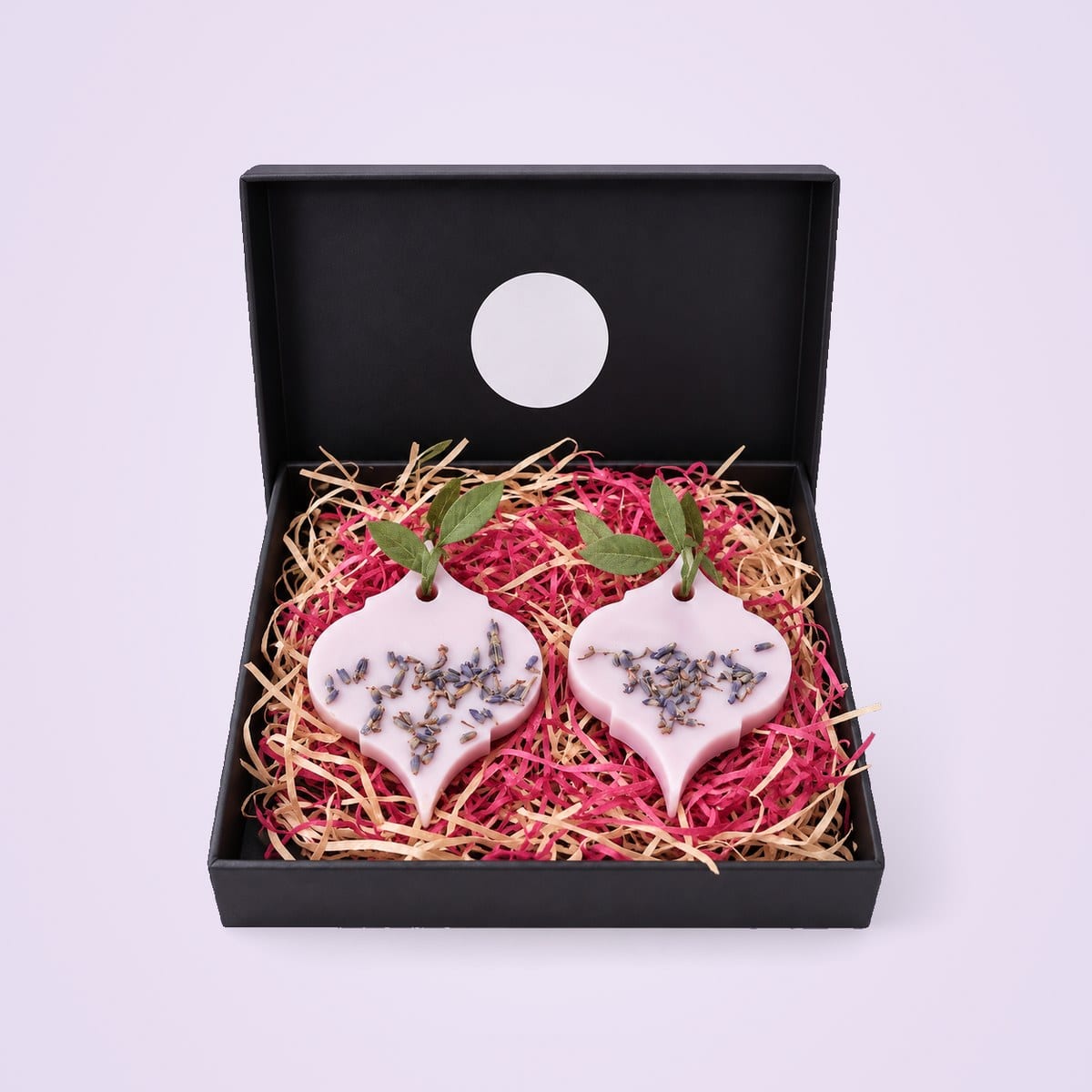 Two lilac arabesque wax sachets with lavender buds in a black gift box