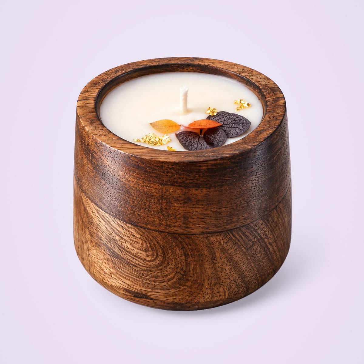 Dark wooden jar candle topped with petals and gold flakes